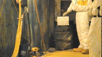 A worker holds a sign identifying the last of 14,500 drums to be removed in the cargo container extraction project. A worker holds a sign identifying the last of 14,500 drums to be removed in the cargo container extraction project.