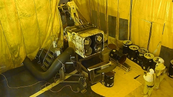 Retrieval operators in an inner contamination enclosure empty a bin of its drums. Retrieval operators in an inner contamination enclosure empty a bin of its drums.
