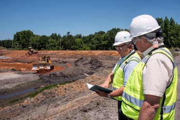 SRNS environmental engineers Ron Socha (left) and Frank Sappington inspect earth-moving work within a basin containing coal ash. SRNS environmental engineers Ron Socha (left) and Frank Sappington inspect earth-moving work within a basin containing coal ash.