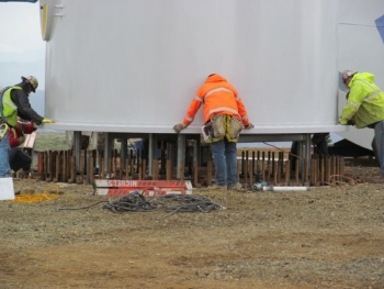 Workers line up bolts as a wind tower section is lowered at the Eva Creek Wind Farm site. The project supported 180 jobs during the construction phase. | Photo courtesy of Golden Valley Electric Association Workers line up bolts as a wind tower section is lowered at the Eva Creek Wind Farm site. The project supported 180 jobs during the construction phase. | Photo courtesy of Golden Valley Electric Association