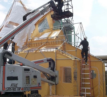 A worker climbs the stairs of a radioactive waste processing containment hut built on a specially-designed, free-standing frame. A worker climbs the stairs of a radioactive waste processing containment hut built on a specially-designed, free-standing frame.