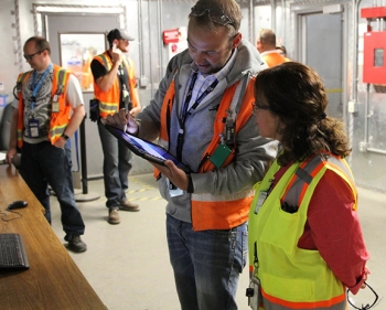 EM Assistant Secretary Monica Regalbuto, right, views the mobile device EM Idaho Site Facility Representative Nicholas Balsmeier, center, has been testing since February. With this tool, Balsmeier can easily access procedures and DOE orders and record notes that can be sent directly to EM and contractor personnel. EM Assistant Secretary Monica Regalbuto, right, views the mobile device EM Idaho Site Facility Representative Nicholas Balsmeier, center, has been testing since February. With this tool, Balsmeier can easily access procedures and DOE orders and record notes that can be sent directly to EM and contractor personnel.