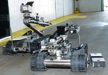 Two PackBots designed and built by Endeavor Robotics with mounted radiation sensor/communication are prepared for the demonstration. Two PackBots designed and built by Endeavor Robotics with mounted radiation sensor/communication are prepared for the demonstration.