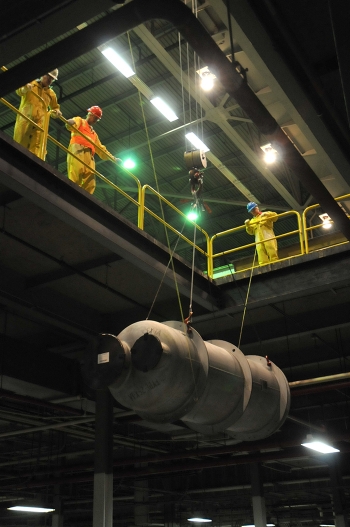 Workers lower process gas equipment from a cell for analysis and packaging. Workers lower process gas equipment from a cell for analysis and packaging.