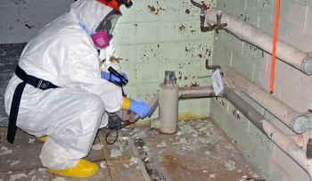 A technician surveys a pipe for contamination. A technician surveys a pipe for contamination.