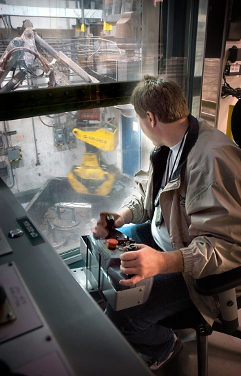 An AMWTP operator manipulates a robotic arm while sorting waste in an AMWTP boxline. An AMWTP operator manipulates a robotic arm while sorting waste in an AMWTP boxline.