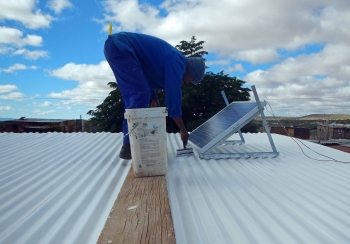 A worker paints a rooftop with reflective paint in the !Khies municipality in Northern Cape, South Africa. | Photo by Mothusi Guy of PEER Africa A worker paints a rooftop with reflective paint in the !Khies municipality in Northern Cape, South Africa. | Photo by Mothusi Guy of PEER Africa