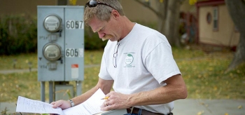 A worker reviews paperwork while standing next to a control box.