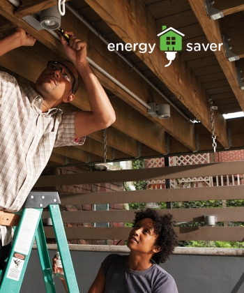 Photo of a man on a ladder doing electrical work, while a woman stands beside him to assist. Photo of a man on a ladder doing electrical work, while a woman stands beside him to assist.