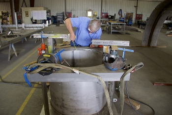 A project engineer with EM contractor North Wind, inspects fabrication of a new hatch cover.