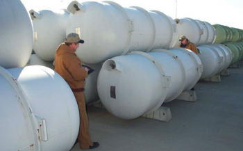 Workers inspect one of the thousands of specially designed storage cylinders that hold DOE's inventory of more than 740,000 metric tons of depleted uranium hexafluoride (DUF6).