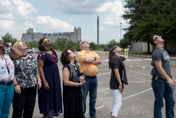 SRS employees look up at the eclipse. In the background is the Defense Waste Processing Facility (DWPF), the nationâs only operating vitrification facility that converts high-level radioactive waste into a glass form safe for long-term storage.