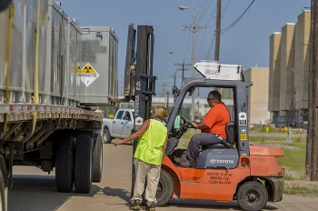 Personnel load a flat-bed truck for an off-site shipment.