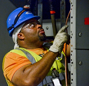 An electrician installs new wiring as part of a site electrical reconfiguration project.