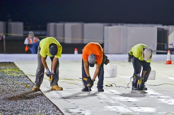 Workers install new roof surfacing on a site building.
