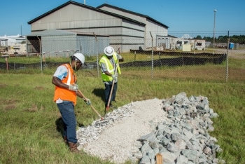Savannah River Nuclear Solutions employees Dakota Williams (left) and Mandrell Crawford create a mound of oyster shells to absorb unwanted metals in rainwater runoff bound for a nearby stream.