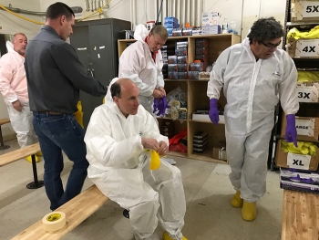 DOE Under Secretary for Science Paul Dabbar (center) dons protective clothing prior to entering the air lock of the 324 Building, located about 300 yards west of the Columbia River.