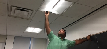 Photo of a man inspecting a light fixture.