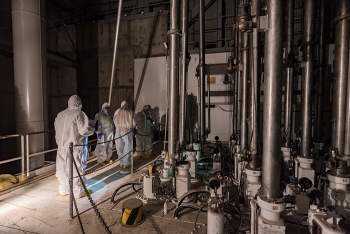 Workers inspect vertical safety rods in the K East Reactor above the reactor core. Control rods were used to regulate plutonium production during the Cold War.