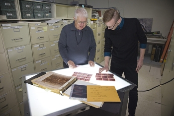 Dan Ostergaard (left) and Nolan McCants with Mission Support Alliance look through historical photos in EMâs Hanford Site collection. Old photos are critical to current cleanup planning.