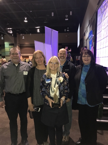 (Left to right) Mission Support Alliance employees Mike Wilson, Dru Butler, Bob Wilkinson, and Amy Basche congratulate Ann Shattuck (front) on her award during the Tri-City Regional Chamber of Commerce 2018 Women in Business conference.