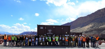 Employees hold signs denoting the milestone of relocating 9 million tons of uranium mill tailings from the Moab Site.