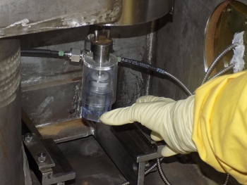 An operator takes a sample of process solution in the sample aisle at H Canyon. Under the initiative to improve spent nuclear fuel processes, online monitors will eliminate the need to pull samples for lab analysis during routine process operations.