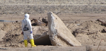 A radiological control technician prepares to survey concrete debris uncovered during excavation of soil.
