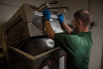 Scientist Mike Cantaloub uses a piece of equipment designed by WSU students at one of PNNLâs laboratories.