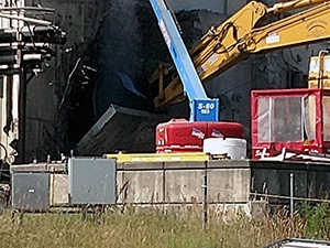 Heavy equipment lowers the 60-ton transfer tunnel shield door to the ground.