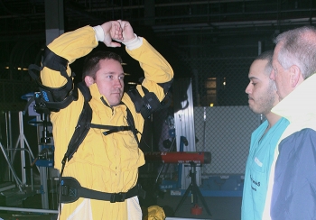 Portsmouth Non-Destructive Assay Technician Damon Horn, left, demonstrates how the lift assist of the exoskeletal device helps hold his arms in position.