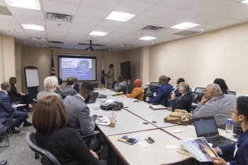 Conference attendees viewing a presentation around a conference table.