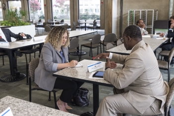 Shows an MBED representative meeting during a one on one session across a table.