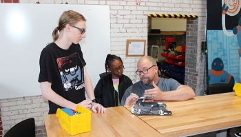 Sprocket Director Jimi Gwinn, right, uses circuit boards to teach Paducah students Chris McVickers, left, and Miya Patterson about computer technology.