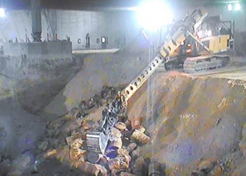 Crews use an excavator with an extended boom to exhume buried waste at the Accelerated Retrieval Project facilities at the Idaho National Laboratory Site.