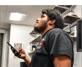 Photo of a man holding a phone and looking up.