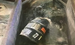 Waste containing roaster oxides is emptied from a drum into a tray at the Accelerated Retrieval Project prior to being raked through with an excavator.
