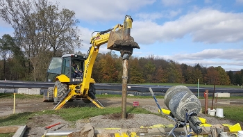 A backhoe is used to pull the well pump and casing from the ground after workers stabilized the casing with grout.