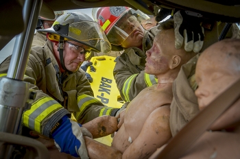 Fire Chief Darrell Howard, left, and Jake Mason stabilize rescue mannequins during a vehicle extrication simulation.