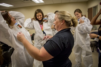 Four Rivers Nuclear Partnership employee Elizabeth Wyatt teaches students how to âdonâ and âdoffâ personal protective equipment.