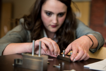 WSU student Jacqueline Reeve assembles an apparatus that bends the metal filament to hold samples for thermal ionization mass spectrometer analysis at PNNL.