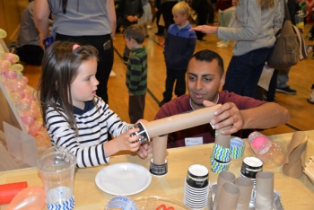 Sandia systems engineer Raheel Mahmood shows a student how to construct a roller coaster track for marbles.