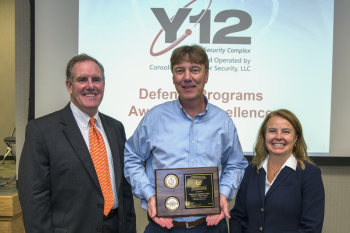 Brian Gullett, center, accepts his teamâs Award of Excellence from NNSA Assistant Deputy Administrator for Major Modernization Programs Michael Thompson and NNSA Production Office Deputy Manager Teresa Robbins.