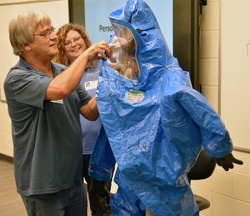 Classroom instructors Billy Edington and Pam Gray help a student put on personal protective gear correctly.