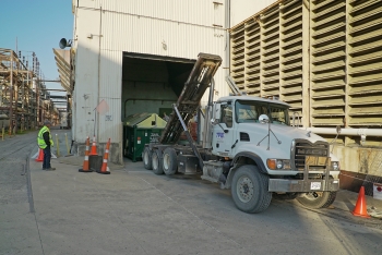 Workers relocate a debris container from the Alpha 4 heating area to the fogging demonstration area at the Oak Ridge Site.