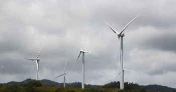 Five wind turbines at varying heights with clouds in the background.