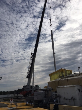 Workers use a crane to move a new pump to a Tank 41 riser for installation.