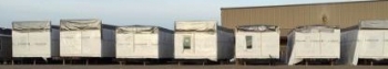 A row of storage containers lined up in a parking lot.