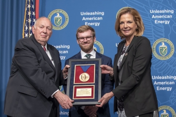 Ambassador Linton Brooks, left, and NNSA Administrator Lisa Gordon-Hagerty, right, present the 2019 Linton Brooks Award to Kyle Fowler.