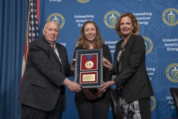 Ambassador Linton Brooks, left, and NNSA Administrator Lisa Gordon-Hagerty, right, present the 2019 Linton Brooks Award to Jessica Lillo.